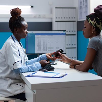 African american doctor explaining sickness symptoms to sick patient discussing medication treatment during clinical appointment. Therapist monitoring disease working in hospital office